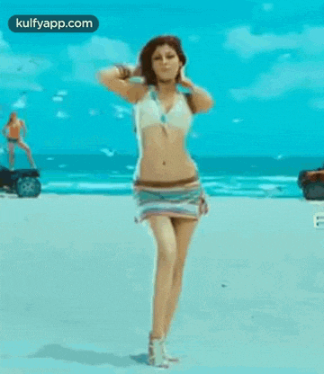 a woman in a bikini is squatting down on a beach .