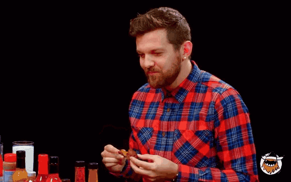 a man in a plaid shirt says i see you while eating a chicken nugget