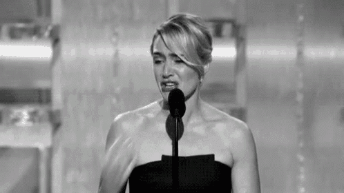 a black and white photo of a woman speaking into a microphone at an awards ceremony .