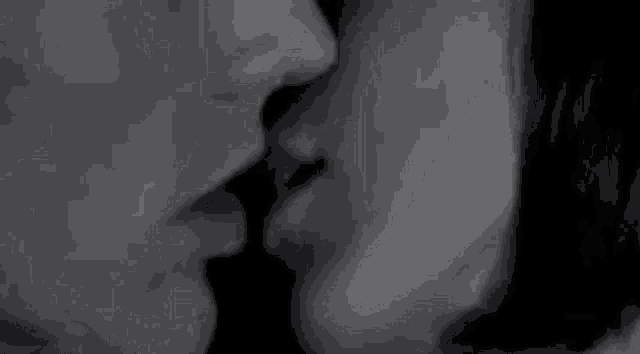 a black and white photo of two people kissing each other .