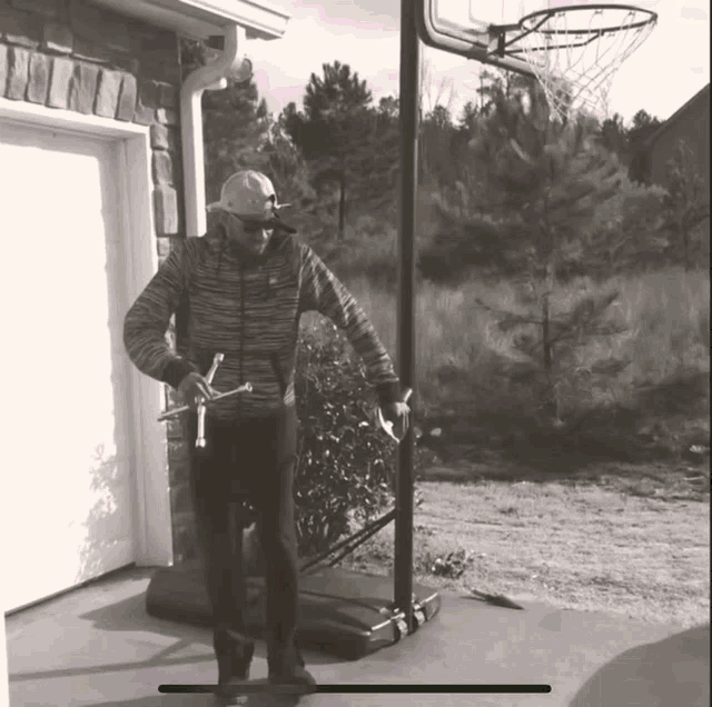 a man standing next to a basketball hoop holding a wrench