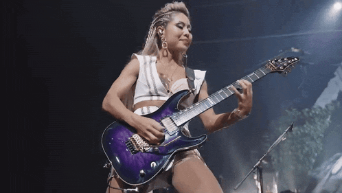a woman playing a purple electric guitar on stage