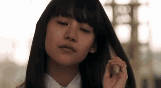 a close up of a woman 's face with her eyes closed while holding her hair .