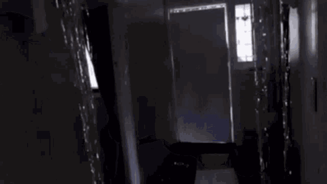 a person is carrying a large piece of furniture through a doorway in a dark hallway .