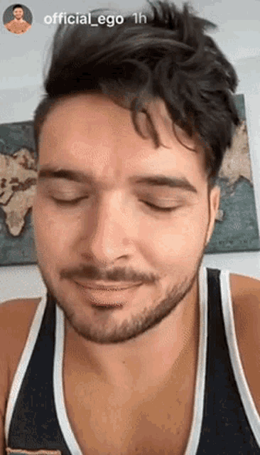 a man with a beard is wearing a black tank top and smiling .