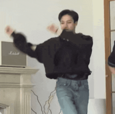 a man in a black sweater is dancing in a living room .