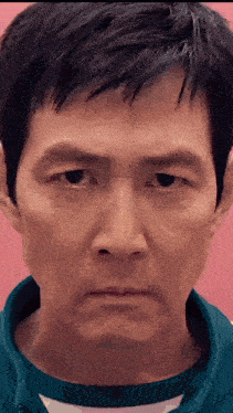 a close up of a man 's face with a pink background and a blue shirt .
