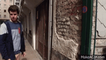 a man is walking down a sidewalk next to a brick wall and a no parking sign
