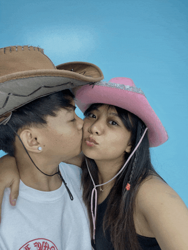a man and woman wearing cowboy hats are kissing
