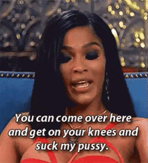 a woman in a red dress is sitting on a blue couch and saying you can come over here and get on your knees