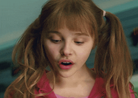 a close up of a girl with pigtails and a pink shirt