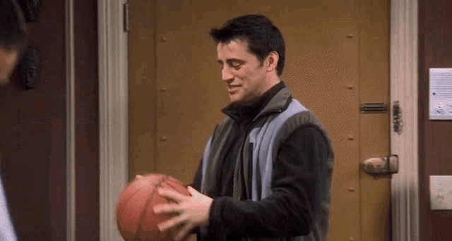 a man is holding a basketball in front of a door