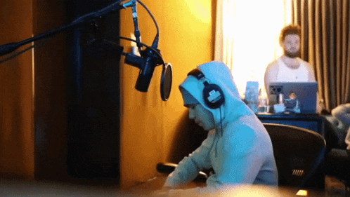 a man wearing headphones is sitting in front of a microphone and a laptop