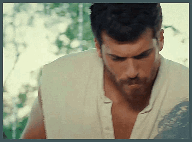 a shirtless man with a beard is looking down