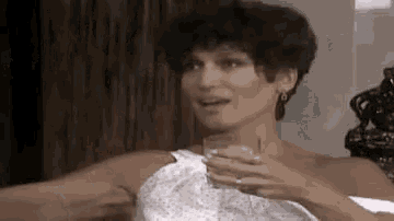 a woman in a white dress is holding a glass of wine in her hand .