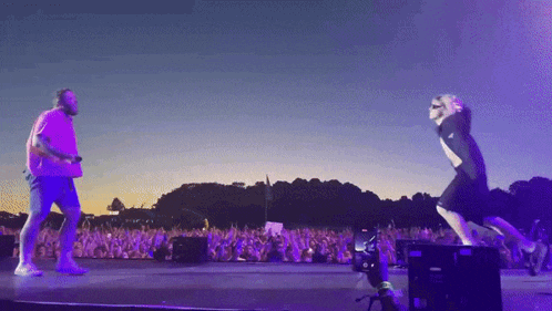 a man and a woman are dancing on a stage in front of a crowd at a concert .