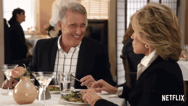 a man and woman are sitting at a table with a netflix logo on the bottom