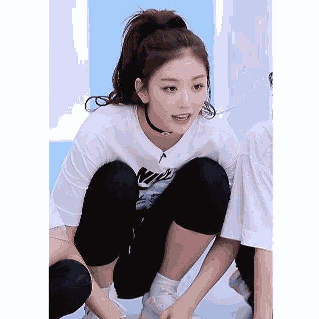 a woman wearing a white nike t-shirt squatting down