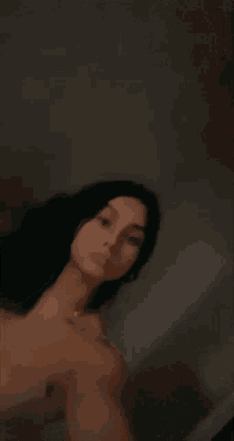 a woman is taking a selfie in a dark room with her eyes closed .