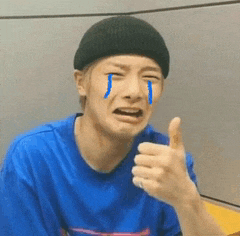 a man is crying and giving a thumbs up while wearing a beanie .