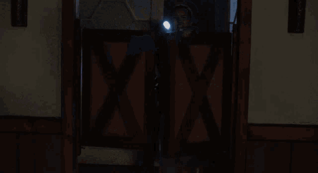 a woman is holding a flashlight in her hand while walking through a doorway