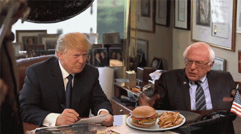 donald trump and bernie sanders sit at a table with a plate of french fries and a hamburger on it