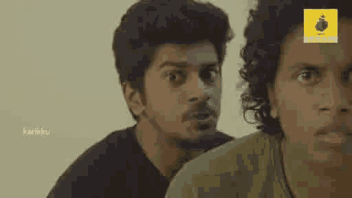 a couple of men are standing next to each other and looking at the camera .