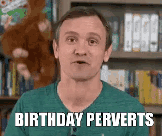 a man in a green shirt is standing in front of a bookshelf and says birthday perverts .