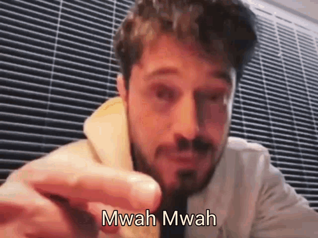 a man with a beard is making a funny face while holding a piece of food .
