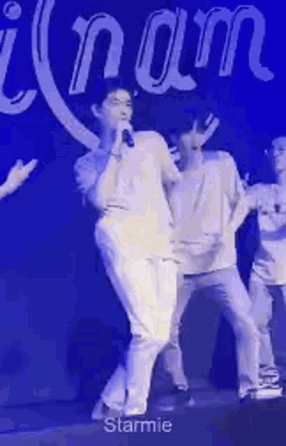 a man is singing into a microphone on a stage while dancing .