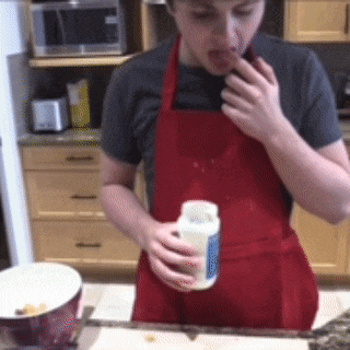 a person wearing a red apron is holding a bottle of mayonnaise