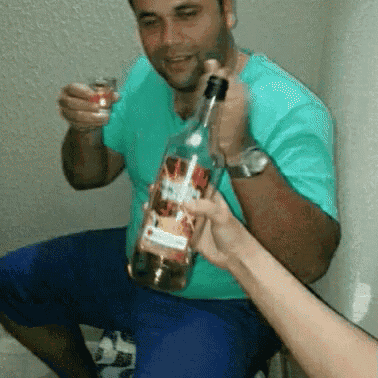 a man in a green shirt is holding a bottle of rum and a shot glass