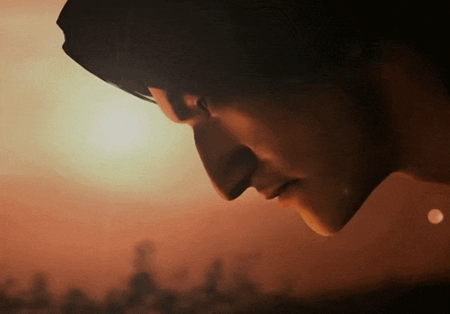 a close up of a person 's face with the sun behind him