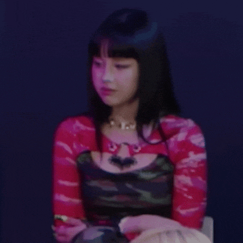 a woman is sitting in a chair wearing a red top and a black dress .