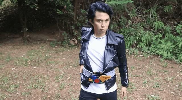a young man is wearing a leather jacket and a belt .