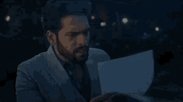 a man with a beard is holding a piece of paper in his hand .