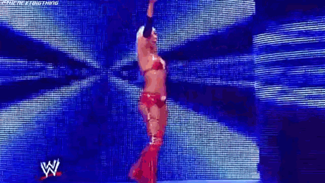 a woman in a red outfit is dancing on a stage in front of a blue background .