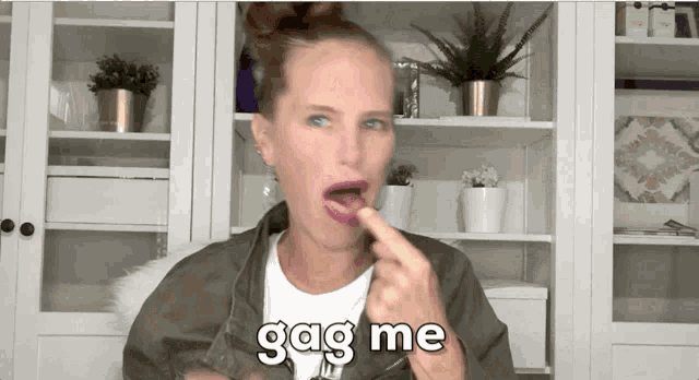 a woman in a green jacket is licking her lips and says gag me .