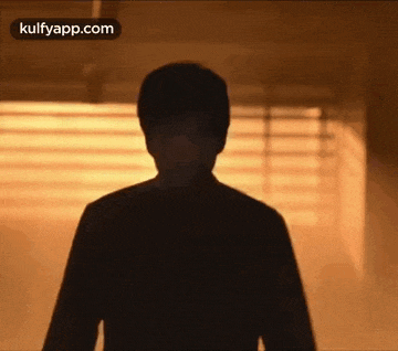 a silhouette of a man standing in a dark room in front of a window .
