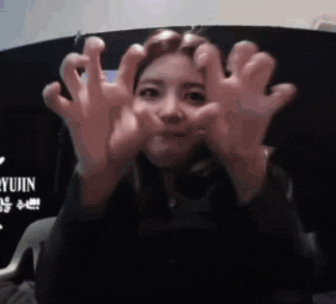 a woman is making a funny face with her hands in front of her face .
