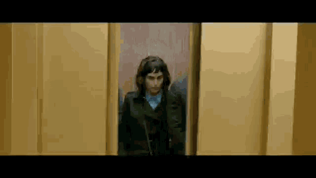 a woman is standing in an elevator looking out of the door .