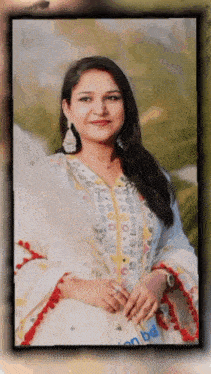 a woman wearing a white and yellow dress with a red border is smiling for the camera