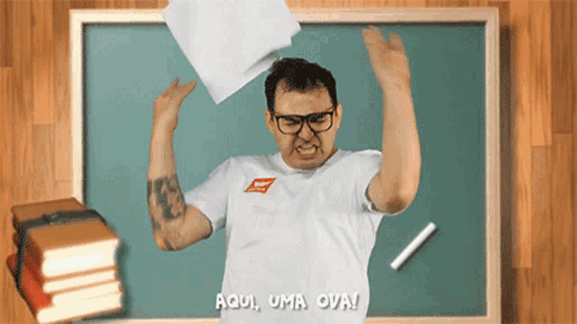 a man throws a piece of paper in front of a chalkboard that says aqui uma ova