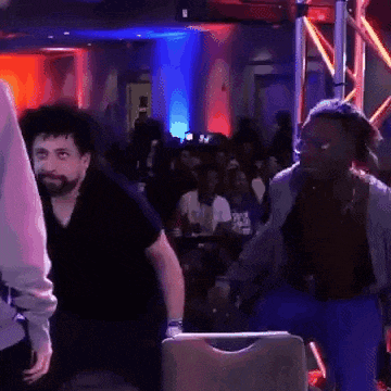 a man with a beard is standing in front of a crowd in a room .