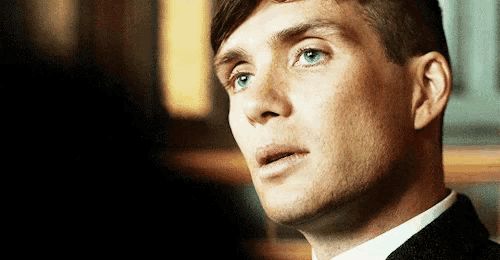 a close up of a man 's face with blue eyes and a black suit .