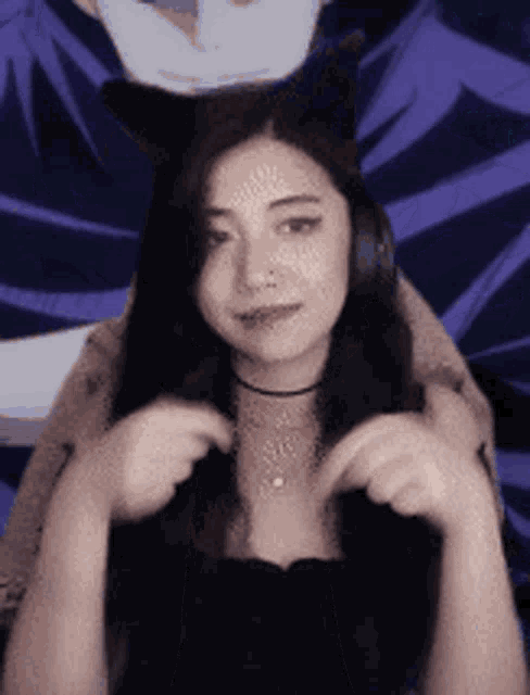 a woman wearing a cat ear headband looks at the camera .
