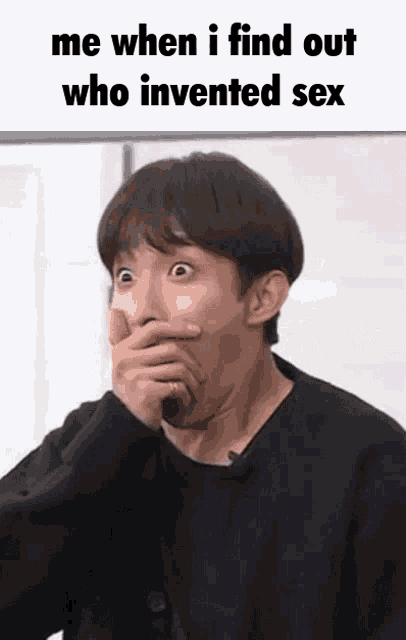 a man is covering his mouth with his hand while making a funny face .