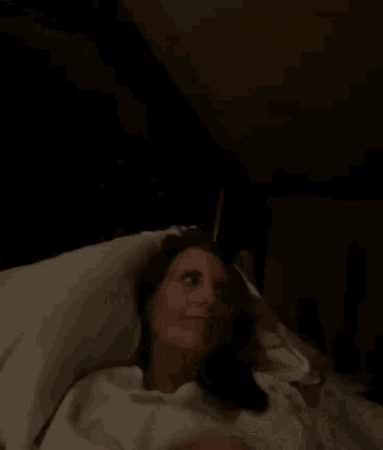 a woman is laying in bed with her head on a pillow .
