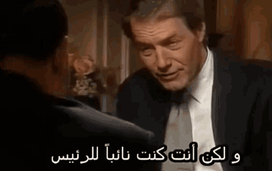 a man in a suit and tie is talking to another man in a foreign language