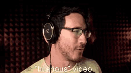 a man wearing headphones and glasses is making a peace sign while saying hilarious video .